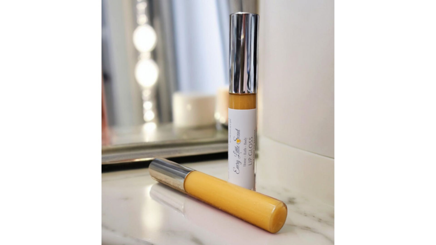 Lucious handmade lip gloss with added vitamin E. image is of one lip gloss stood up and one lied down another Every Little Scent product