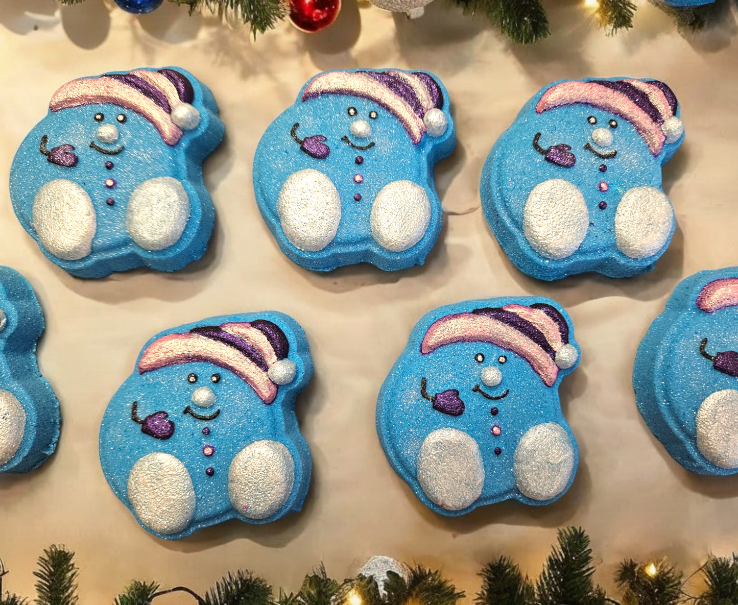 An array of blue bath bombs shaped like snowmen, each wearing a santa hat and white feet