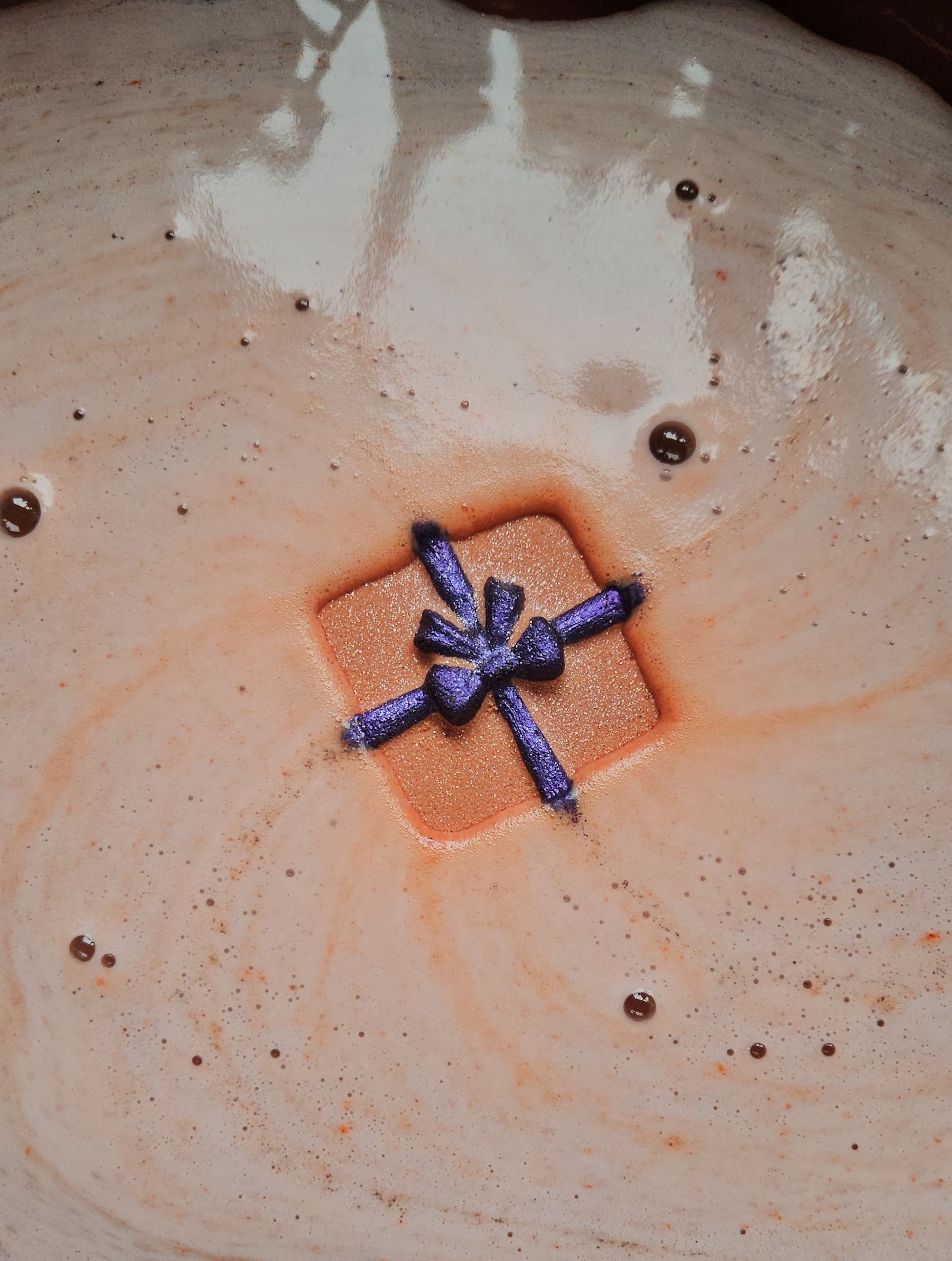Foaming bath bomb in a christmas present design in orange and purple
