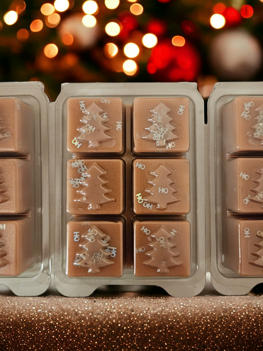 A set of brown wax melt tarts shaped like Christmas trees, with a gingerbread swirl design, packaged in clear clamshell containers.