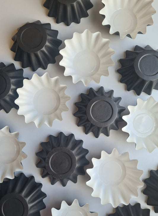 A collection of wax melting liners black in colour, ,designed to fit into a burner to prevent wax melt from sticking.